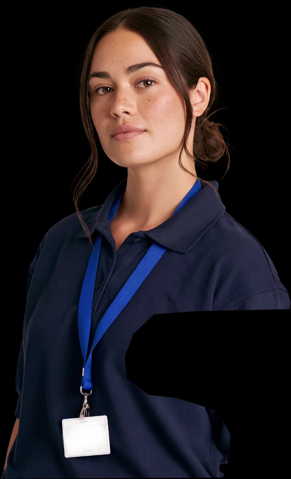 A nurse in a navy polo wearing a lanyard and ID badge, looking to camera